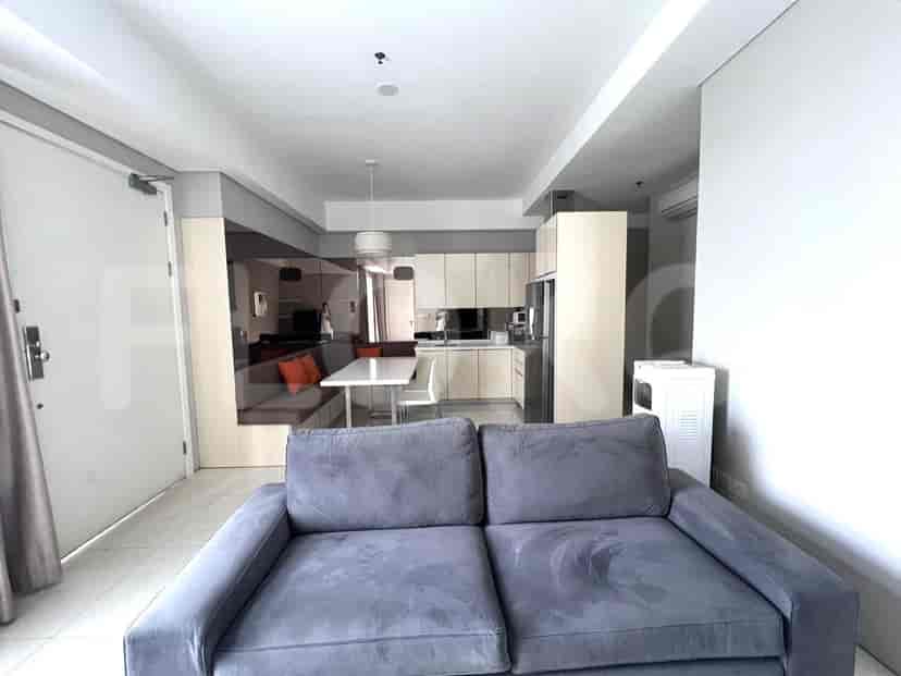 A bright open-plan living area with a sofa, dining table, and kitchen, featuring mirrored walls and light-colored cabinets.