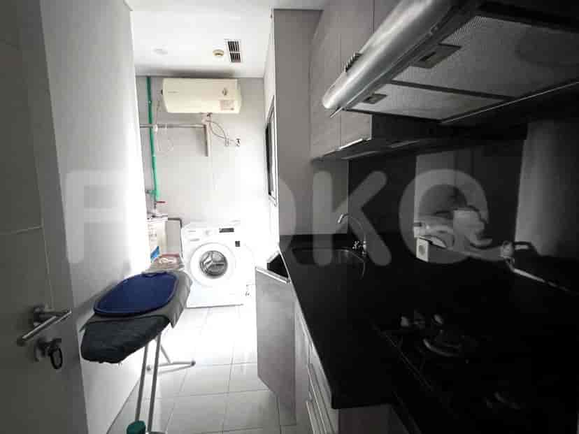 A compact kitchenette area with a stove, sink, and a laundry area with a washing machine and ironing board.