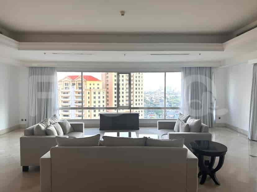 Ruang tamu luas dengan jendela besar yang menawarkan pemandangan kota, dilengkapi beberapa sofa dan meja kopi.
