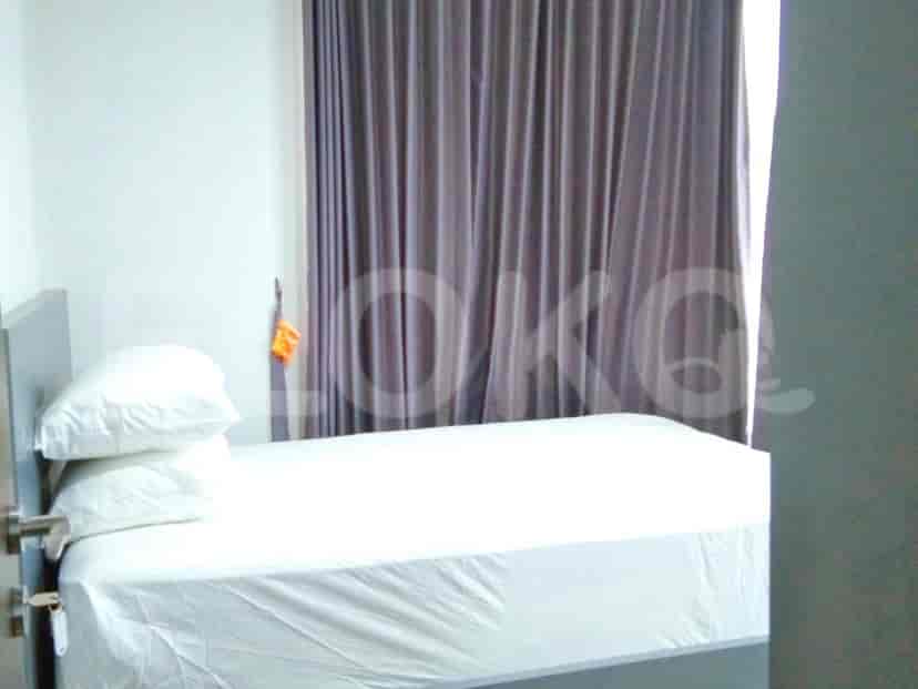 A bedroom with a single bed, white bedding, and a grey curtain.