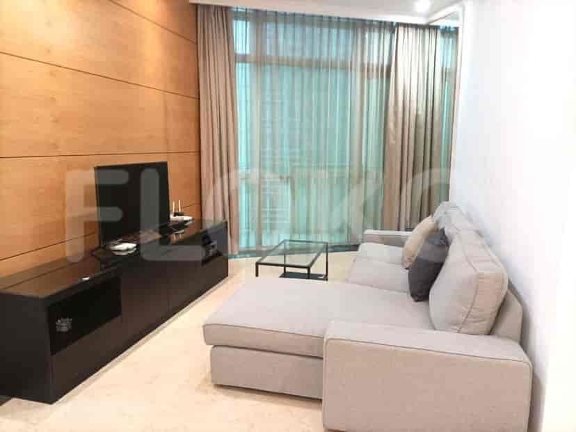 Modern living room with grey sectional sofa, a dark wood entertainment unit with a TV, and a glass coffee table.