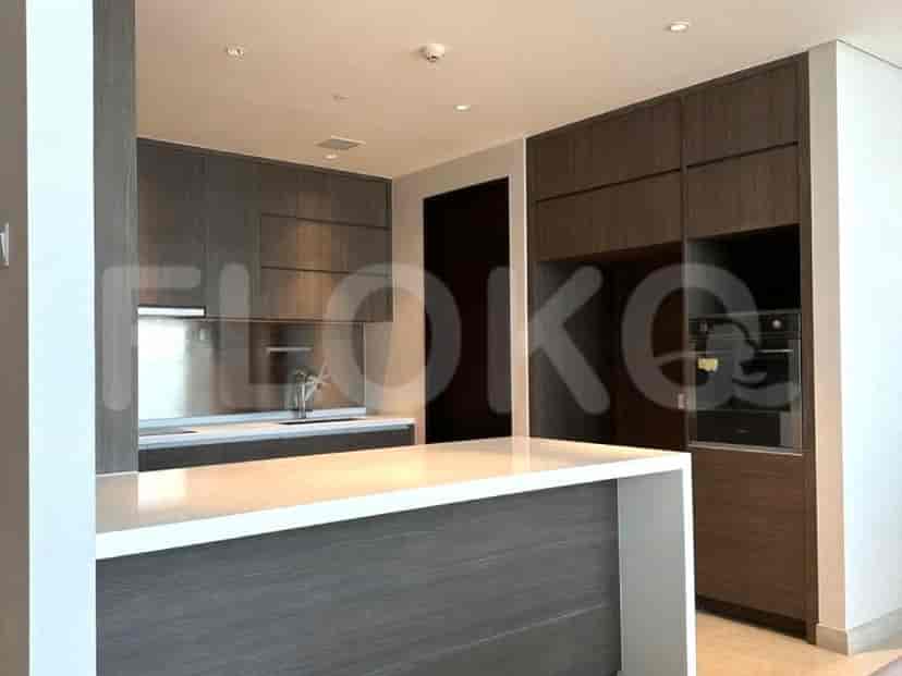 A modern open-plan kitchen with dark wood cabinets, a white countertop island, and built-in appliances.