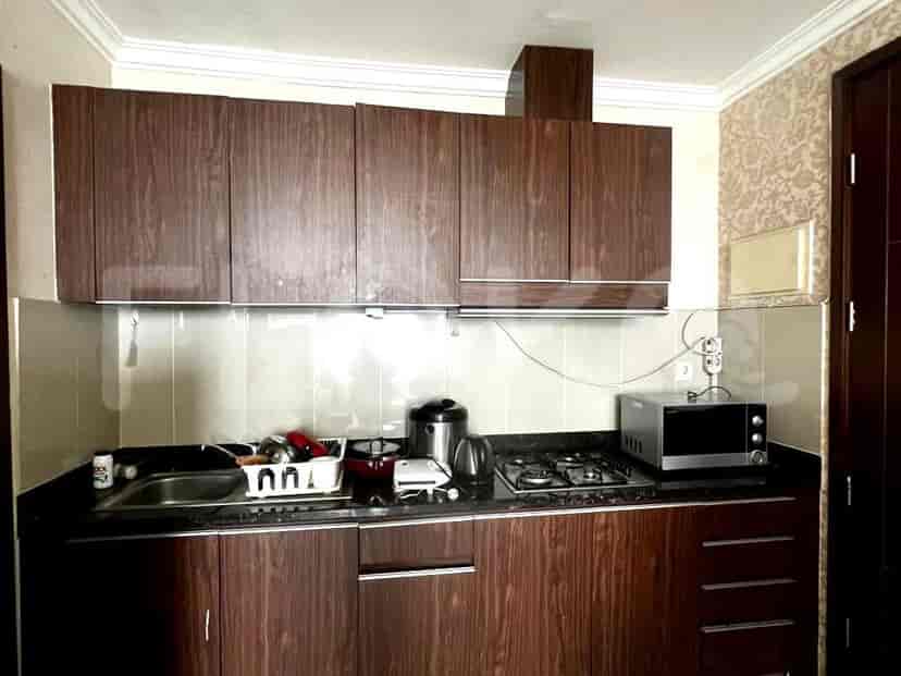 A compact kitchen with dark wood cabinets, a sink, stove, and microwave.