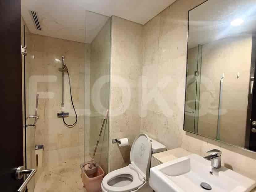 A clean and modern bathroom with beige tiled walls and floor, a walk-in shower with a glass enclosure, and a vanity with a sink and mirror.