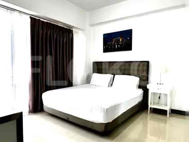 A bedroom with a queen-sized bed, nightstand, and a large window with dark curtains.