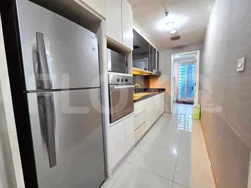 Dapur bergaya galeri yang panjang dengan peralatan stainless steel dan lemari putih.