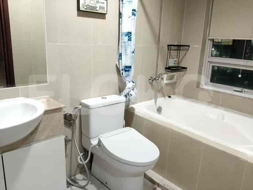 A clean bathroom with a toilet, bathtub, and sink, featuring neutral-toned tiles.