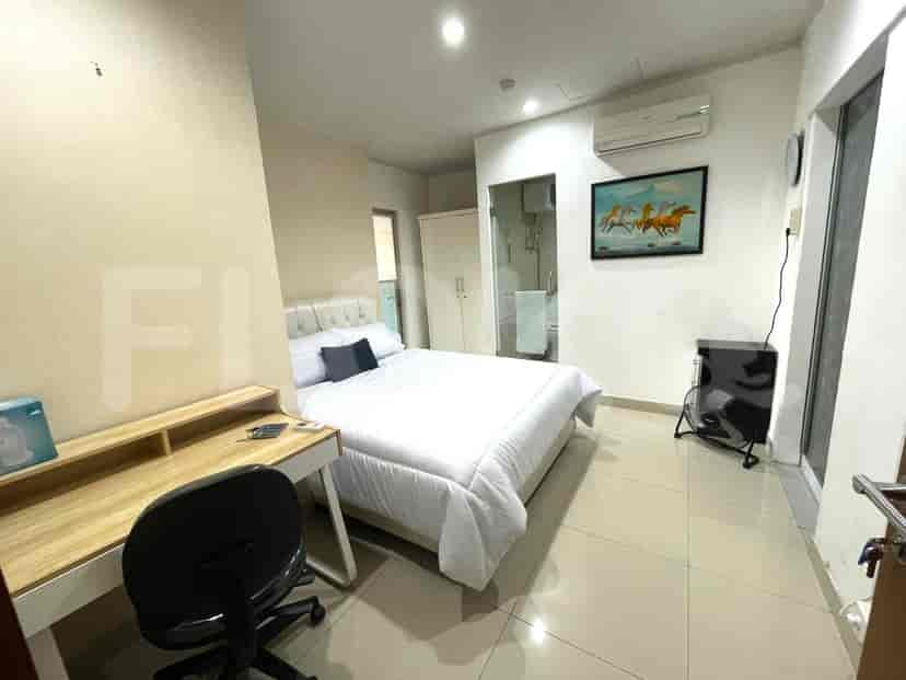 Sebuah kamar tidur dengan tempat tidur queen-size, meja, dan lemari, dengan kamar mandi dalam yang terlihat.