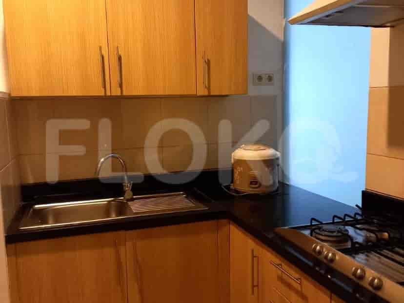 A compact kitchen with wooden cabinets, a sink, stove, and a rice cooker.