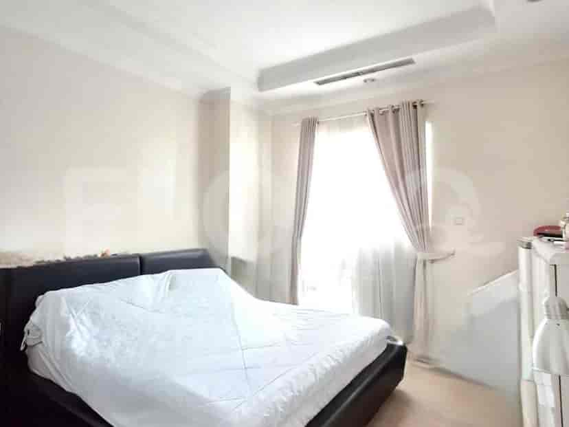 A bedroom with a large bed covered in white bedding, a window with light beige curtains, and white furniture.