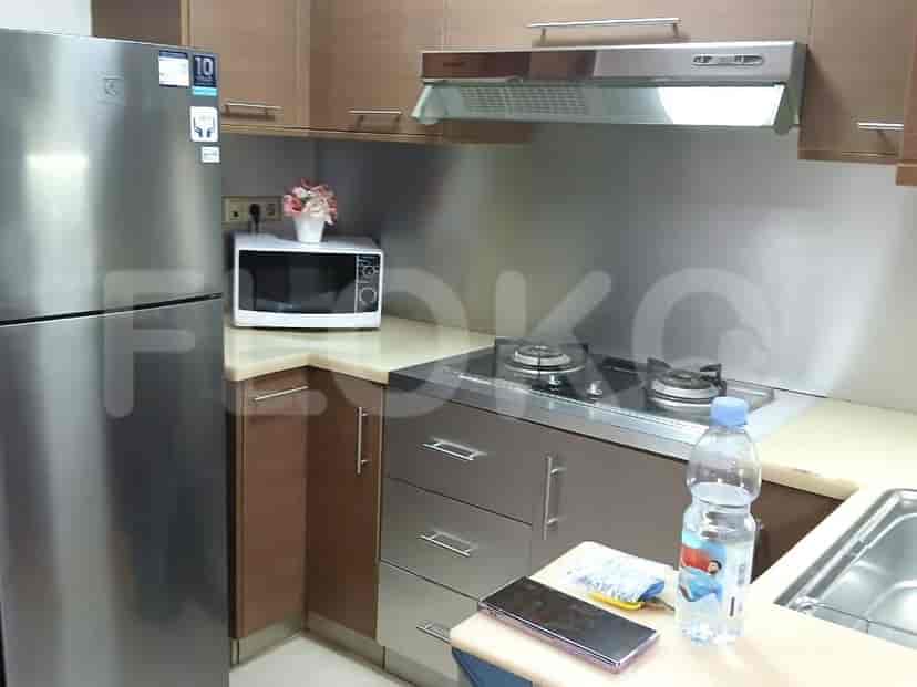 A compact kitchen with stainless steel appliances, including a refrigerator and a gas stove, with overhead cabinets.