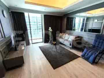 A modern living room with a grey sofa, coffee table, TV stand, and large windows.
