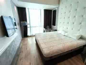 A bedroom with a queen-size bed, large window, and a wall-mounted TV.