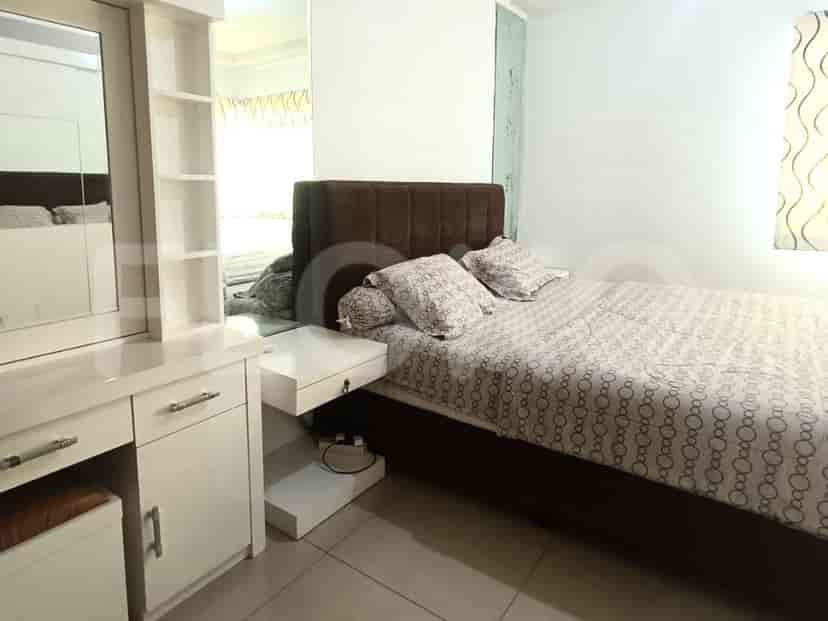A bedroom with a queen-size bed, a white dressing table, and a large mirror.