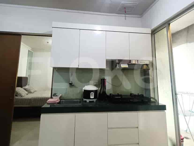 A small kitchen area with white cabinets, a dark countertop, sink, and a gas stove.