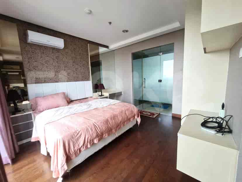 A bedroom with a queen-sized bed, patterned wallpaper, and a glass-enclosed shower.