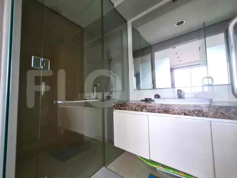 A modern bathroom with a glass-enclosed shower, vanity with sink, and mirrored cabinets.