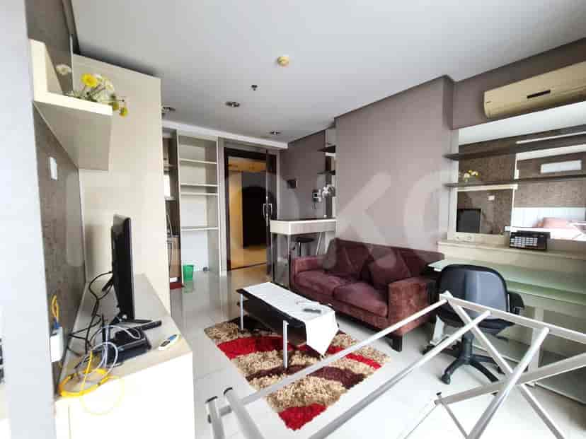 A compact living room with a dark red sofa, a coffee table on a rug, and a TV stand.
