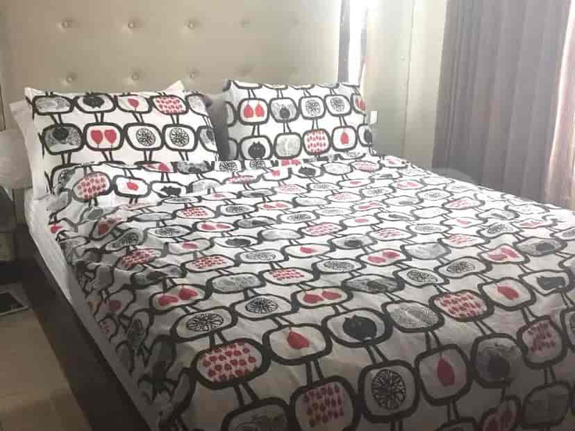 A bedroom with a queen-size bed featuring a patterned duvet cover and a tufted headboard.