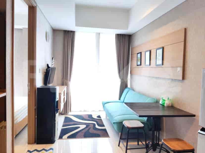 A compact living room with a light blue sofa, a dining table, a TV, and a large window.