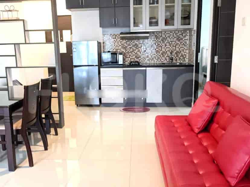 A living area with a red sofa and a dining set, adjacent to a kitchen.