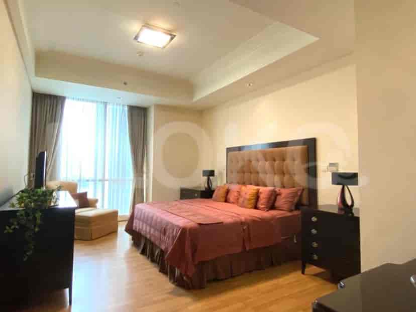 A luxurious master bedroom with a king-size bed, large window with curtains, and dark wood furniture.