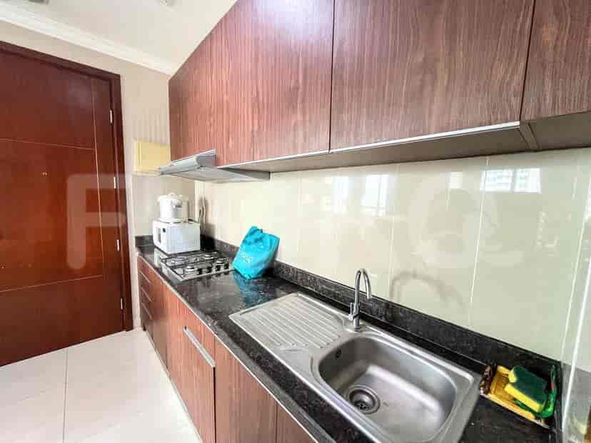 A compact kitchen with dark wood cabinets, a granite countertop, a gas stove, and a sink.