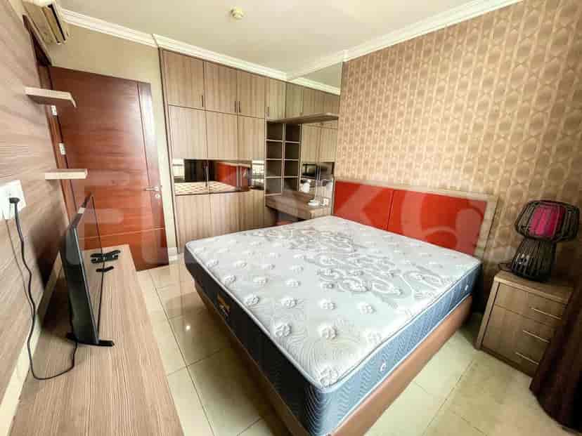 A bedroom with a large bed, built-in wardrobes, a dresser, and a television.