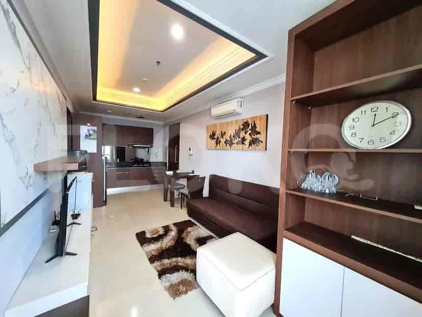 A combined living room and kitchen area with a sofa, TV, dining table, and kitchen counter.