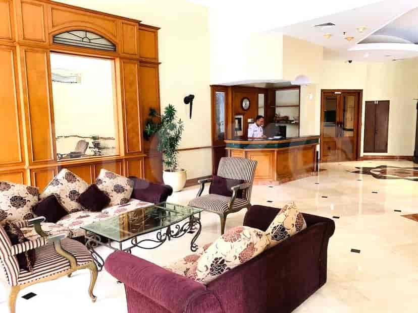 A hotel lobby with a reception desk, seating area, and wooden paneling.