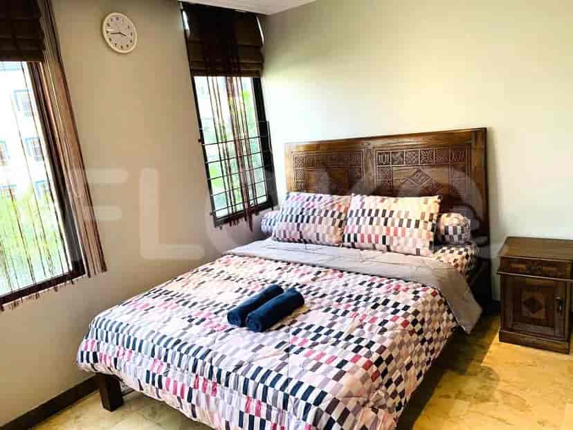 A bedroom with a queen-size bed, bedside table, and a window.