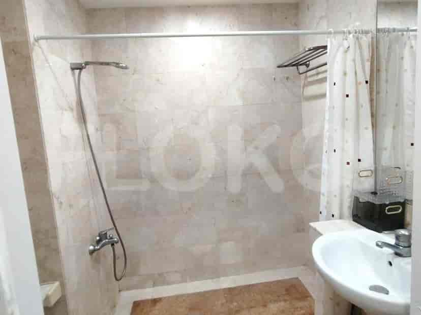 A bathroom with tiled walls, a shower area with a curtain, and a sink.