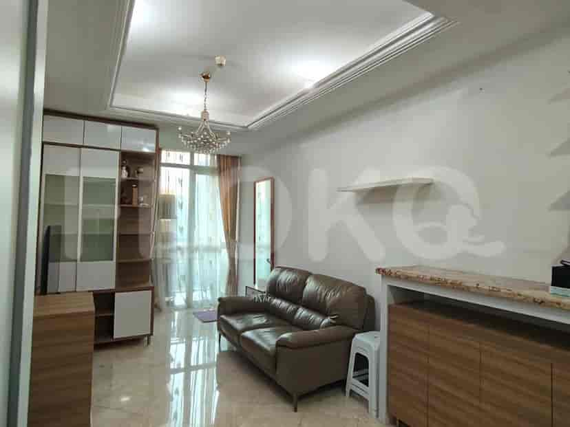 A living room with a brown leather sofa, a large window with curtains, and a wall unit.