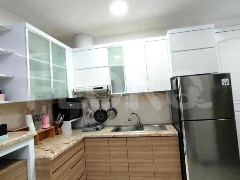 A modern kitchen with white cabinets, wooden lower cabinets, and a stainless steel refrigerator.