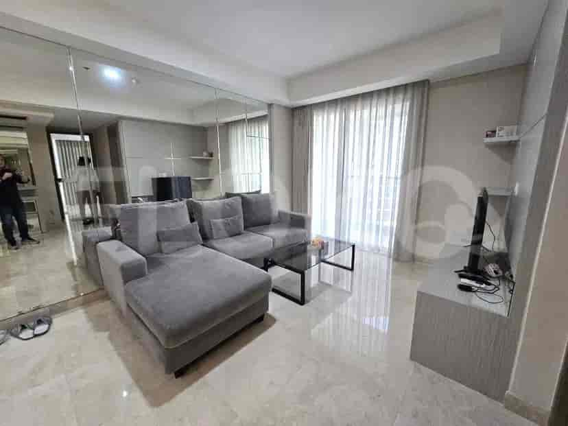 A modern living room featuring a grey sectional sofa, a glass coffee table, and a wall of mirrors.