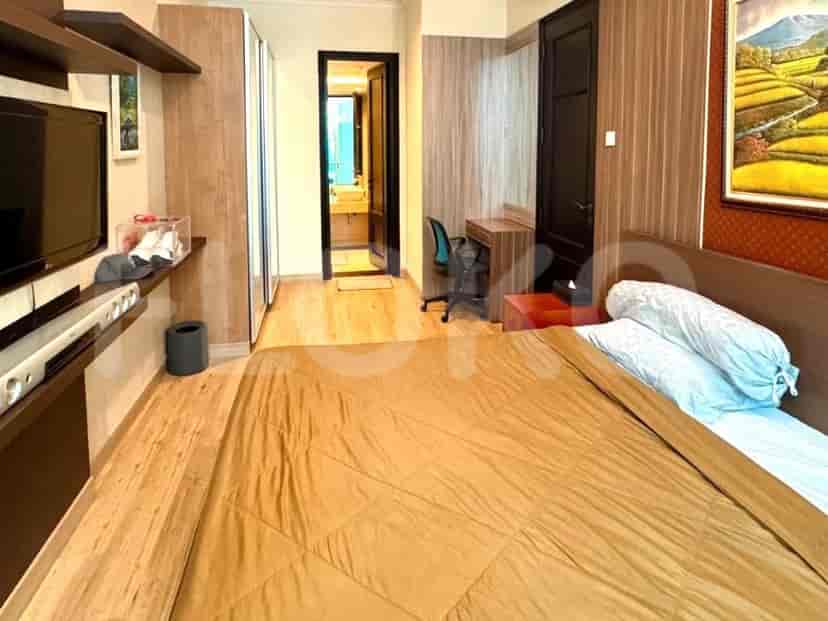 A bedroom with a large bed, a wooden desk, and a closet.