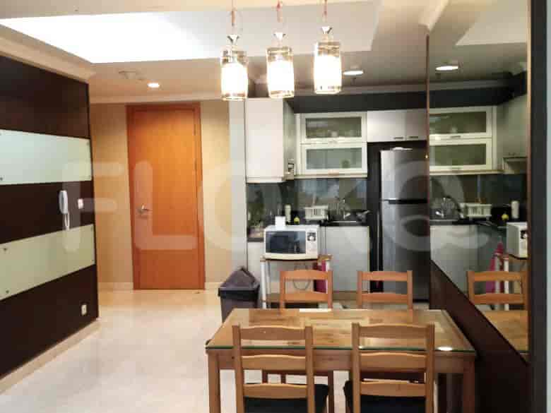 A dining area with a wooden table and chairs, adjacent to an open kitchen with appliances.