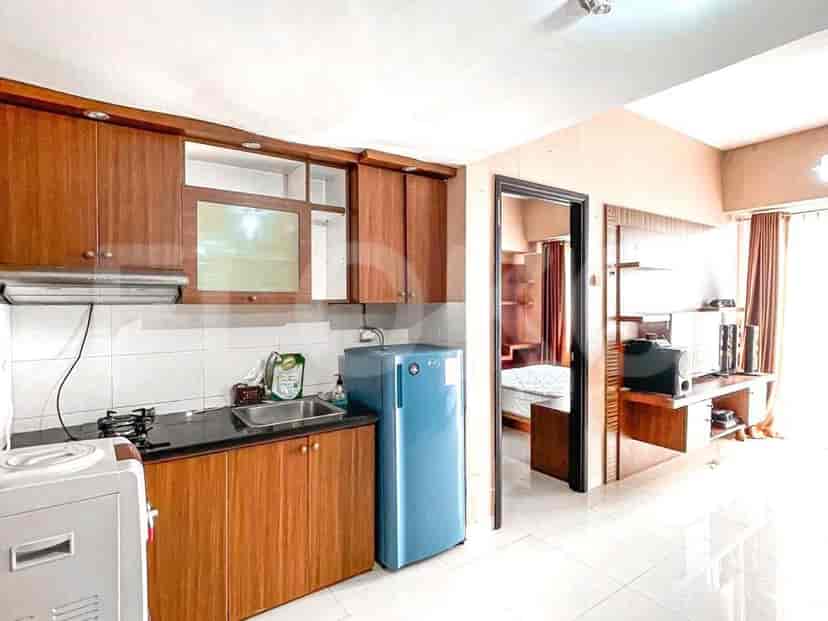 A compact kitchen with wooden cabinets, a black countertop, a sink, a blue refrigerator, and a gas stove.