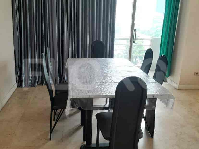 A dining table set for six, covered with a plastic tablecloth, surrounded by black chairs.