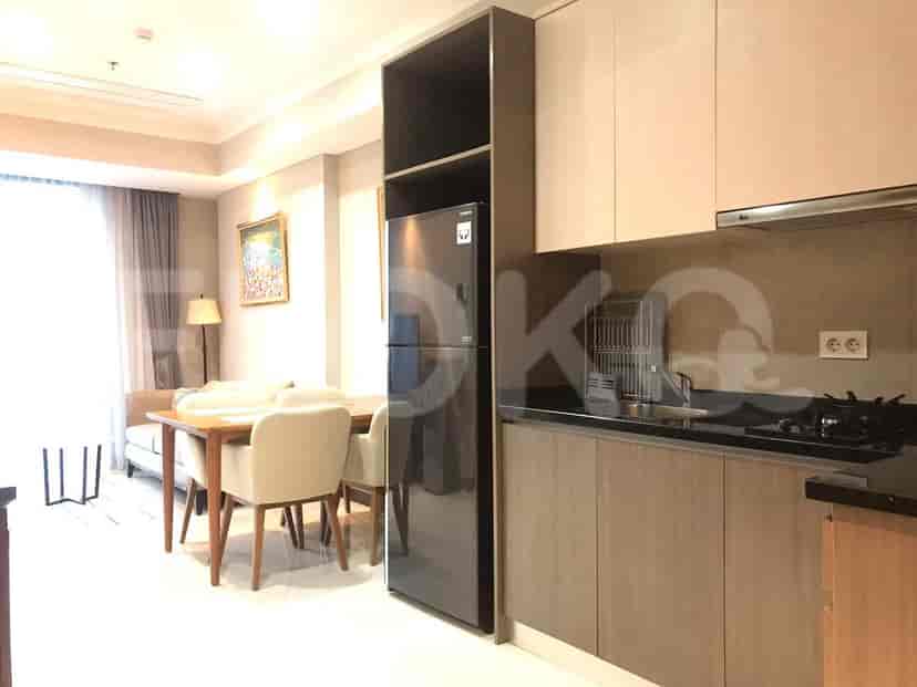 Dapur modern dengan lemari kayu terang, meja dapur hitam, dan kulkas besar.