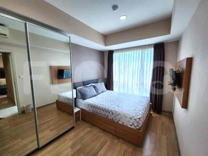 A room with a large window offering a city view, a desk with a chair, and shelves.