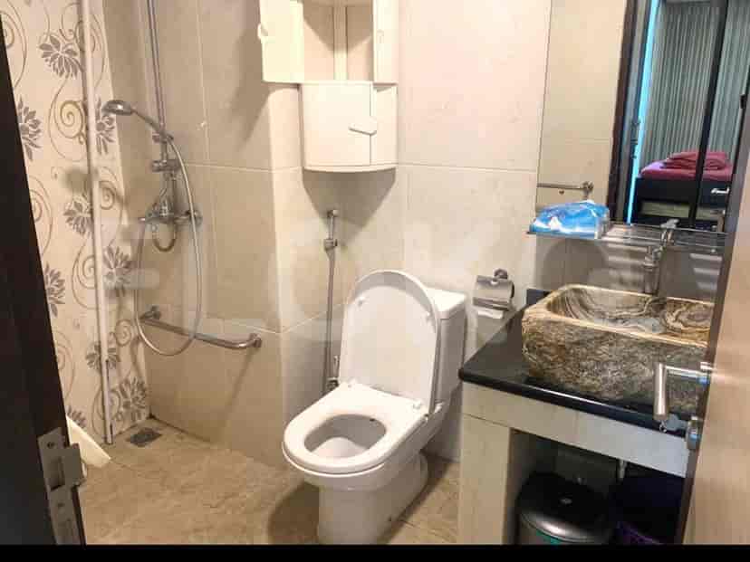 A bathroom with a toilet, sink, shower area, and storage.