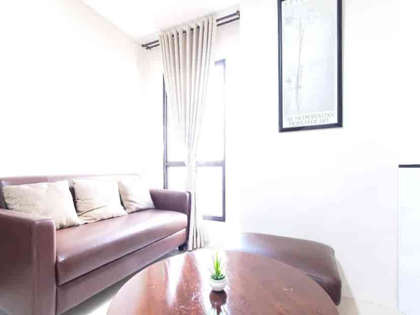 A living room with a brown leather sofa, a round coffee table, and a framed artwork on the wall.