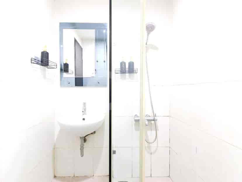 A small bathroom with a sink, mirror, and a glass-enclosed shower.