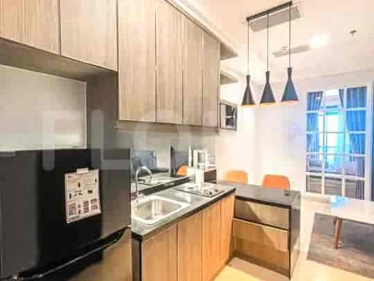 A small kitchen area with cabinets, a sink, and a refrigerator.