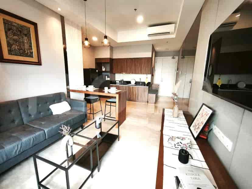 A modern living room with a grey sofa, coffee table, and an open-plan kitchen area.