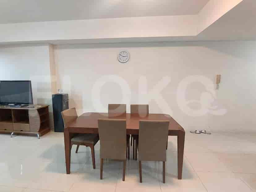 A dining room with a wooden table and chairs, and a television.