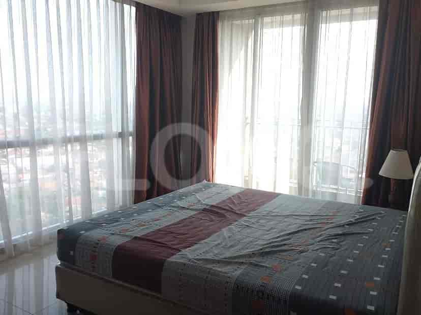 A bedroom with a bed and large windows with curtains.
