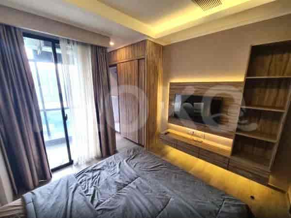 A bedroom with a large bed, a wall-mounted TV, wooden wardrobe, and a balcony door with curtains.