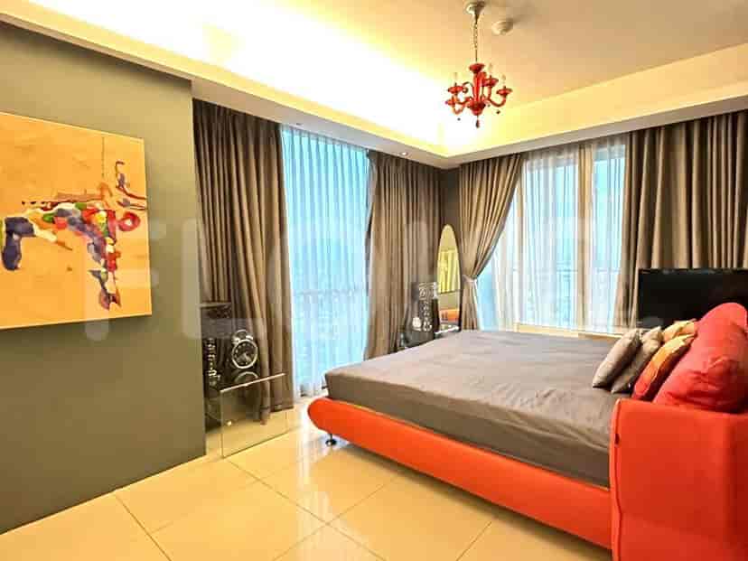 A bedroom with a single bed covered in a yellow sheet, a white desk, and a green chair.